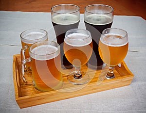 Glasses with different sorts of beer on wooden tray