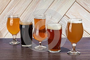 Glasses with different types of craft beer on a wooden bar. In glasses and bottles. Nuts and crackers on the table. On a