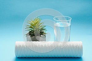 Glasses of dirty and clear water and filter cartridges to domestic water treatment systems at bright blue background. Concept of