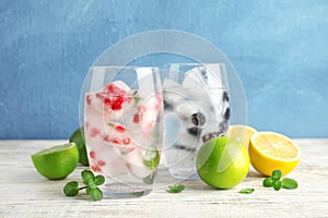 Glasses of drinks with fruit ice cubes on table