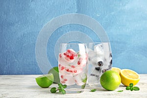 Glasses of drinks with fruit ice cubes on table