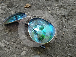 Glasses on earth with reflection of nature and sky in them