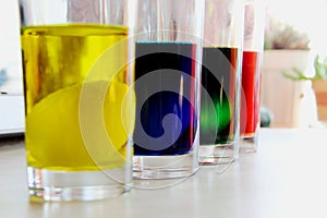 Glasses with eggs in multicolored coloring water. egg in a glass with yellow dye. Easter preparations.