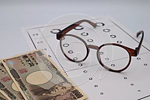 Glasses, eye chart and Japanese banknotes