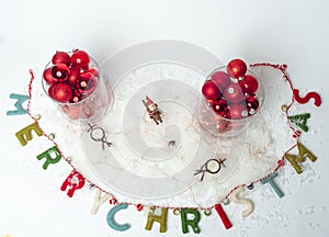 Glasses filled with Christmas ornaments on top of a snow-covered surface