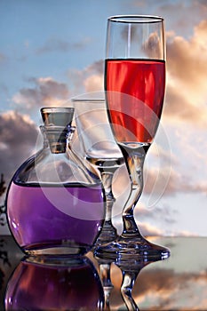 Glasses and flask with sunset background