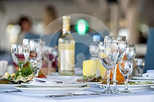 Glasses, forks, knives, napkins and decorative flower on a table served for dinner in cozy restaurant