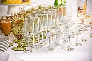 Glasses, forks, knives, napkins and decorative flower on a table served for dinner in cozy restaurant.