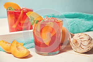 Glasses with fresh homemade peach sweet iced tea or cocktail, lemonade with mint. Refreshing cold drink. Summer party