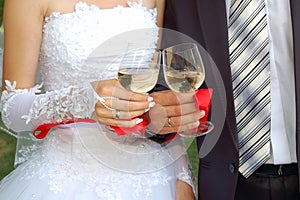 Glasses in the hands of groom and fiancee