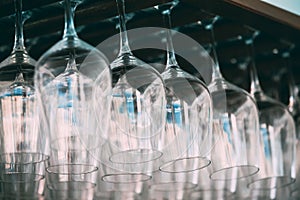 Empty glasses for wine above a bar rack. Hanging wine glasses in a bar