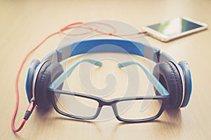 Glasses headphone and smartphone on wood floor