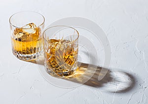 Glasses with ice cubes of single malt whiskey on white background