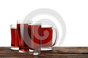 Glasses of kvass on wooden table, white background