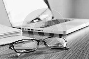 Glasses and laptop on the desk work place in black and white