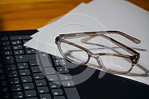 Glasses laptop keyboard and notes on wooden background business concept close up view