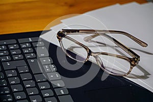 Glasses laptop keyboard and notes on wooden background business concept close up view