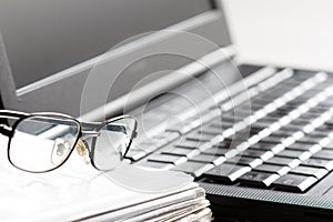 Glasses and laptop on workspace abstract business accounting background