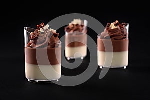Glasses with layered chocolate panna cotta isolated on black.