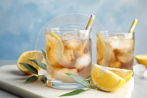 Glasses of lemonade with ice cubes and fruit on table