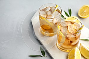 Glasses of lemonade with ice cubes and fruit on table.