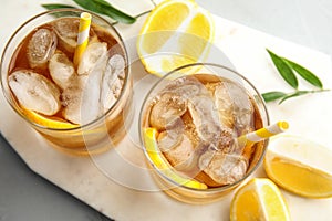 Glasses of lemonade with ice cubes and fruit on table