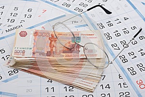Glasses lie on a bundle of five-thousandth Russian banknotes, background from calendar sheets