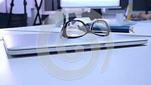 Glasses lie on the laptop on the office desk, close-up