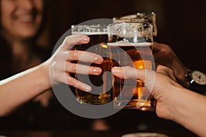 glasses with light beer in hands of happy clinking friends