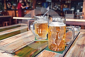 Glasses of light beer on pub background. Pint glass of golden beer with snacks