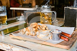 Glasses of light beer on pub background. Pint glass of golden beer with snacks