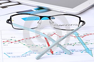 Glasses lying on a business graph analysis report.