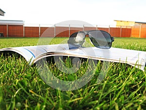 Glasses on the magazine on the grass photo