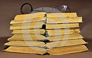 Glasses and magnifying glass on old books on brown background. Literature and historical concept, nostalgia, old age. Ancient