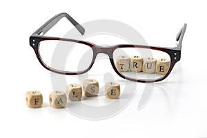 glasses and message - false true - in wooden letter blocks, isolated