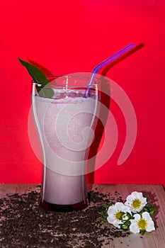 Glasses of milk cocktail with strawberry, ice cream on wooden plate and red background. Sweet drinks for summer concept.