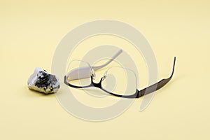 Glasses and moonstone on a yellow background.