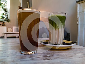 Glasses of nitro cold brew coffee and iced matcha latte standing on wooden table