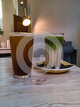 Glasses of nitro cold brew coffee and iced matcha latte standing on wooden table