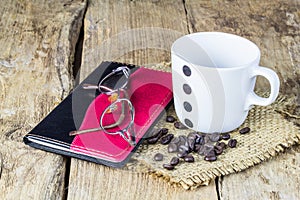 Glasses, notebook, coffee mugs and coffee beans on wooden table