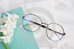 Glasses, notepad and hyacinth flower on white fabric, spring mood concept, spend spring morning on bed