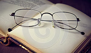 Glasses are on an open old book, vintage