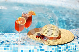 Glasses of orange alcohol cocktail on turquiose water background