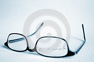 Glasses and paper with E=mc2