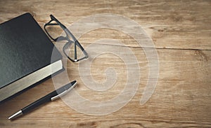 Glasses, pen, book on wooden table