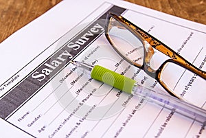 Glasses and pen on salary survey from