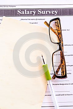 Glasses and pen on salary survey from