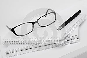 Glasses and pen on white notebook in cell