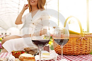 Glasses of Primitivo red wine with happy girl in park defocused on background. Focus on wine glasses photo