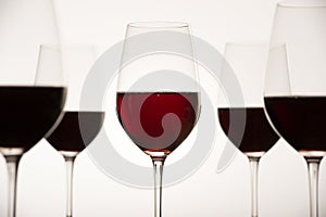 Glasses with red grape wine and bottle on a white glossy surface